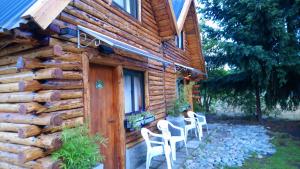 a log cabin with white chairs and a wooden door at CABAÑAS LOS PATOS in Lago Puelo
