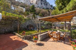 um pátio com uma mesa e cadeiras num jardim em La Gioiella Capri em Capri