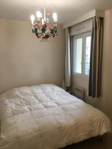 una camera con letto bianco e lampadario pendente di fleur de sel appartement face à la mer a Wimereux
