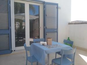 niebieski stół z krzesłami i parasol na patio w obiekcie LI CURTI B&B w mieście Melissano