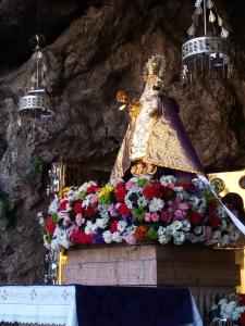 a shrine with a statue on top of flowers at Aldea de Con in Cangas de Onís