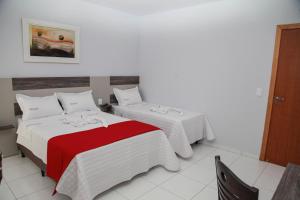 Habitación de hotel con 2 camas con manta roja en Hotel Lorenzetti BR, en Guarapuava
