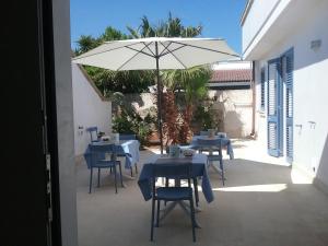 patio ze stołami, krzesłami i parasolem w obiekcie LI CURTI B&B w mieście Melissano