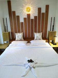 dos camas con sábanas blancas y una flor en ellas en Mingalar Boutique Hotel en Kawthaung