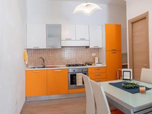 波爾托桑泰爾皮迪奧的住宿－Appartamento Il canto della Luna，厨房配有橙色和白色的橱柜和桌子