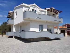 a white house with a balcony on a driveway at Apartment Mia in Bibinje