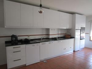 a kitchen with white cabinets and a sink and a refrigerator at The Artist´s Apartment in Espinho +10 photos