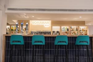 a bar with green stools in a restaurant at Hotel Voramar in Benidorm
