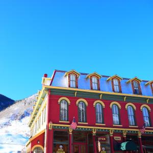 a red building in front of a snow covered mountain at Grand Imperial Hotel in Silverton