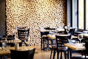 a restaurant with tables and chairs in a room with a wall at Hotel Val de Poix in Saint-Hubert