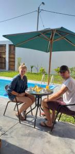 een man en vrouw aan een tafel onder een paraplu bij Diamond Monkey Lodge in Ica