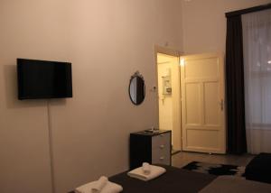 ブダペストにあるDuna Szecsi Apartmanのベッドと壁にテレビが備わるホテルルームです。