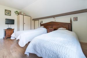 twee bedden in een slaapkamer met witte lakens en een televisie bij Bed and Breakfast Hoorn in Hoorn