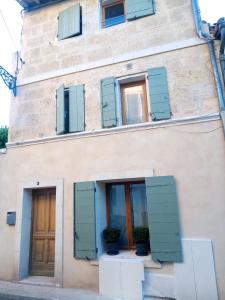 um edifício com janelas azuis fechadas e vasos de plantas em Maison de ville centre arles em Arles
