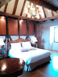 a bedroom with a bed and a table and a chandelier at La Terrasse - Teritoria in Meyronne