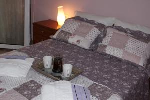 Una cama con una bandeja con dos tazas. en SOUZANA ROOMS 1, en Nea Plagia