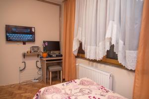a bedroom with a bed and a desk and a window at Rooms Vlado in Daruvar