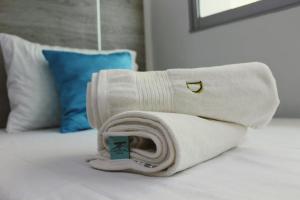 a roll of white towels sitting on a bed at D Río Apartamentos in Ríohacha
