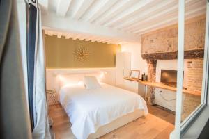 a bedroom with a white bed and a fireplace at La Maison des Arts, Le Six in Honfleur