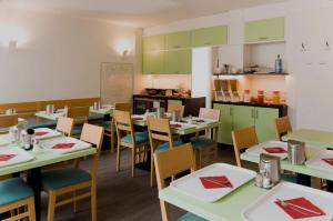 a dining room with tables and chairs and a kitchen at Hotel Royal in Frankfurt