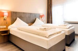 2 Betten in einem Hotelzimmer neben einem Fenster in der Unterkunft Hotel Royal in Frankfurt am Main