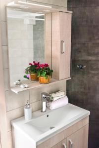 een badkamer met een wastafel, een spiegel en bloemen bij Sea Breeze Experience in Kavala