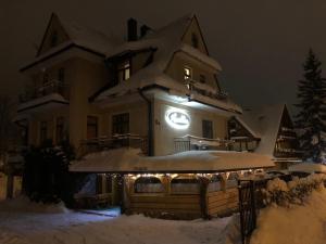 uma casa coberta de neve à noite com luzes em Rusałka em Zakopane