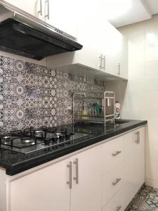 a kitchen with white cabinets and a tile wall at Studio Medina in Rabat