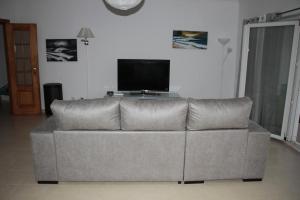 a gray couch in a living room with a tv at Ericeira Sunset Apartment in Ericeira