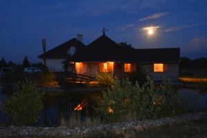 Una casa iluminada por la noche con la luna detrás en Lila Akác Vendégház, en Dabrony