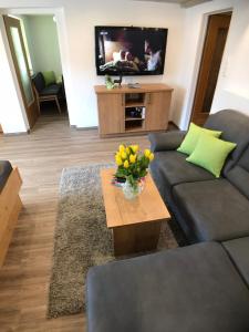 een woonkamer met een bank en een tafel met bloemen bij Gästehaus Amort Ferienwohnung in Ramsau