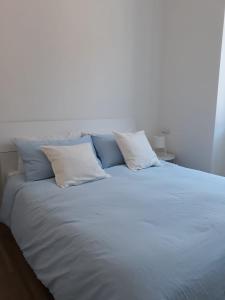 uma grande cama branca com quatro almofadas em Appartamento con vista em Milão