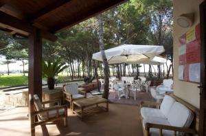 a patio with chairs and tables and an umbrella at Residence Punta Longa in Favignana