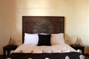a bed with a wooden headboard and white pillows at Riad Sanam - Adults only in Essaouira