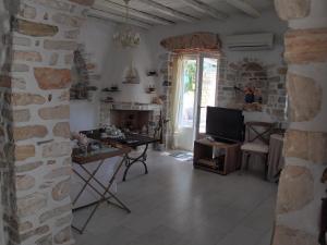 a living room with a stone wall and a television at Villa Petradi (150 meters from the sea) in Ambelas
