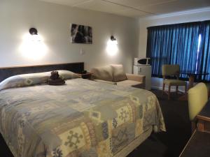 un dormitorio con una cama con un osito de peluche sentado en ella en 100 Mile Motel & RV Park en One Hundred Mile House
