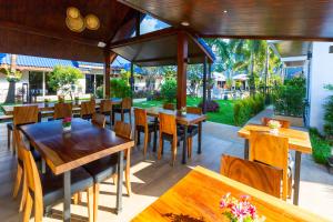 Phuket Airport Hotel - SHA Extra Plus في شاطئ ناي يانغ: مطعم بطاولات وكراسي خشبية وحديقة
