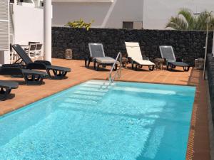 a swimming pool with chaise lounges and chairs around it at Villa Felicidad in Puerto del Carmen