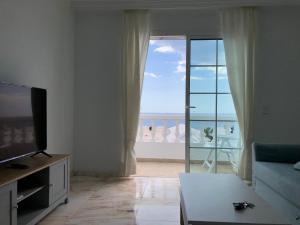 a living room with a television and a view of the ocean at Villa Felicidad in Puerto del Carmen
