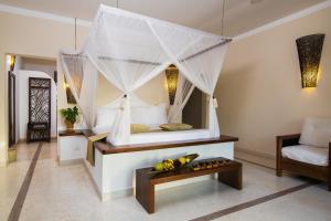 a bedroom with a bed with a canopy at Fruit & Spice Wellness Resort Zanzibar in Kizimkazi