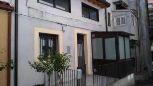 una casa bianca con una porta nera e una recinzione di Gentile holiday house a Catania