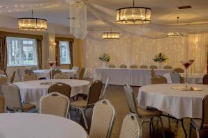 una sala de banquetes con mesas y sillas blancas en Wild Pheasant Hotel & Spa, en Llangollen