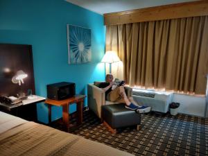 a woman sitting in a chair in a hotel room at Discovery Inn Lafayette in Lafayette