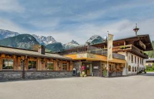 a large building with mountains in the background at Familien- und Vitalhotel Mühlpointhof in Lofer