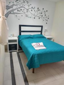 - une chambre avec un lit bleu et un arbre sur le mur dans l'établissement Hotel del Rosario, à Zacatlán