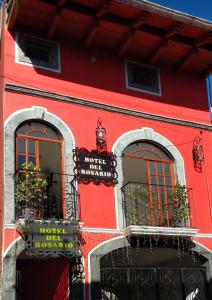 a red building with two windows with plants on them at Hotel del Rosario in Zacatlán