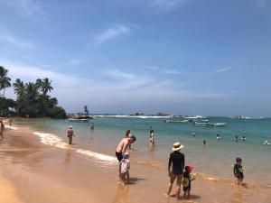a group of people standing in the water at the beach at Siri Tropical Retreat in Hikkaduwa