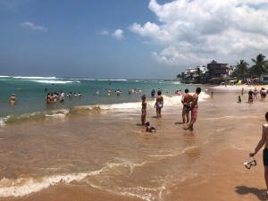 a group of people standing in the water on a beach at Siri Tropical Retreat in Hikkaduwa