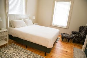 a bedroom with a bed and a chair and two windows at Cape Nelson Lighthouse in Portland