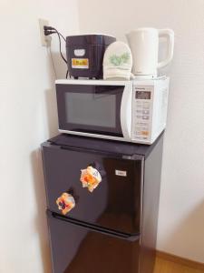 eine Mikrowelle und eine Kaffeemaschine auf dem Kühlschrank in der Unterkunft C.H.House in Tokio
